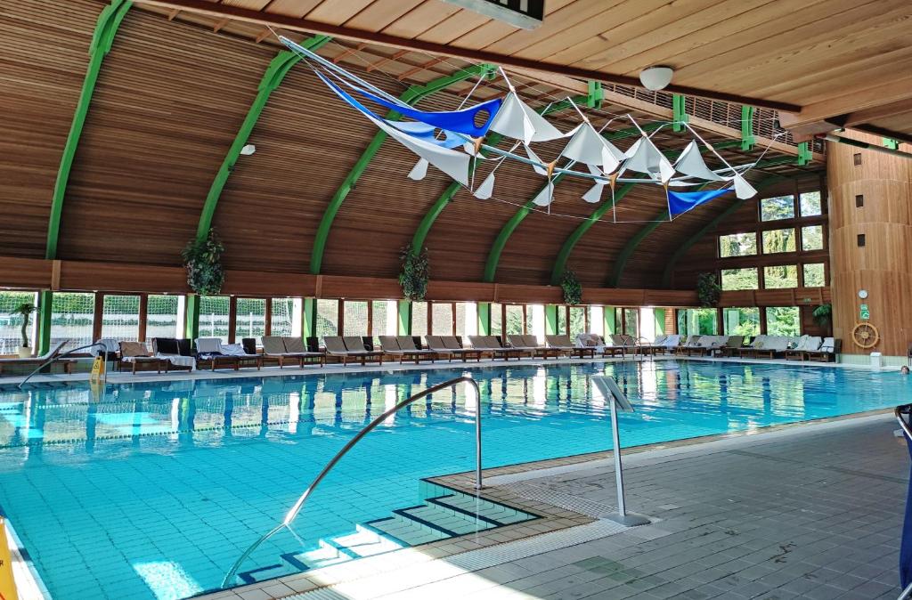 a large swimming pool with tables and chairs in a building at Spa Residence Carbona EmDoNa Luxury Apartment in Hévíz