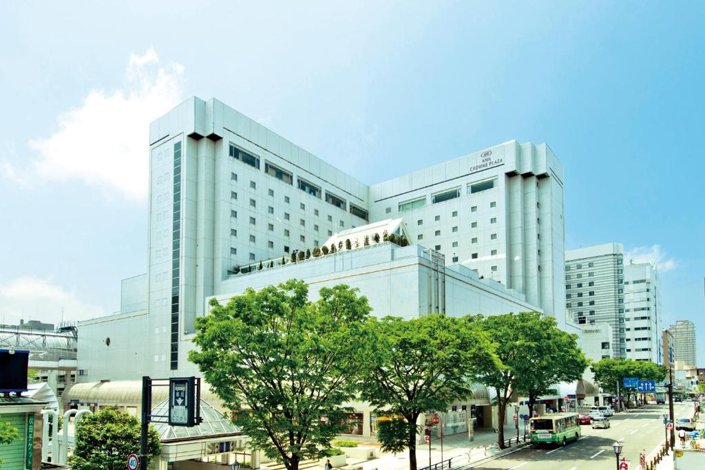 un grand bâtiment blanc avec des arbres devant lui dans l'établissement ANA Crowne Plaza Akita, an IHG Hotel, à Akita