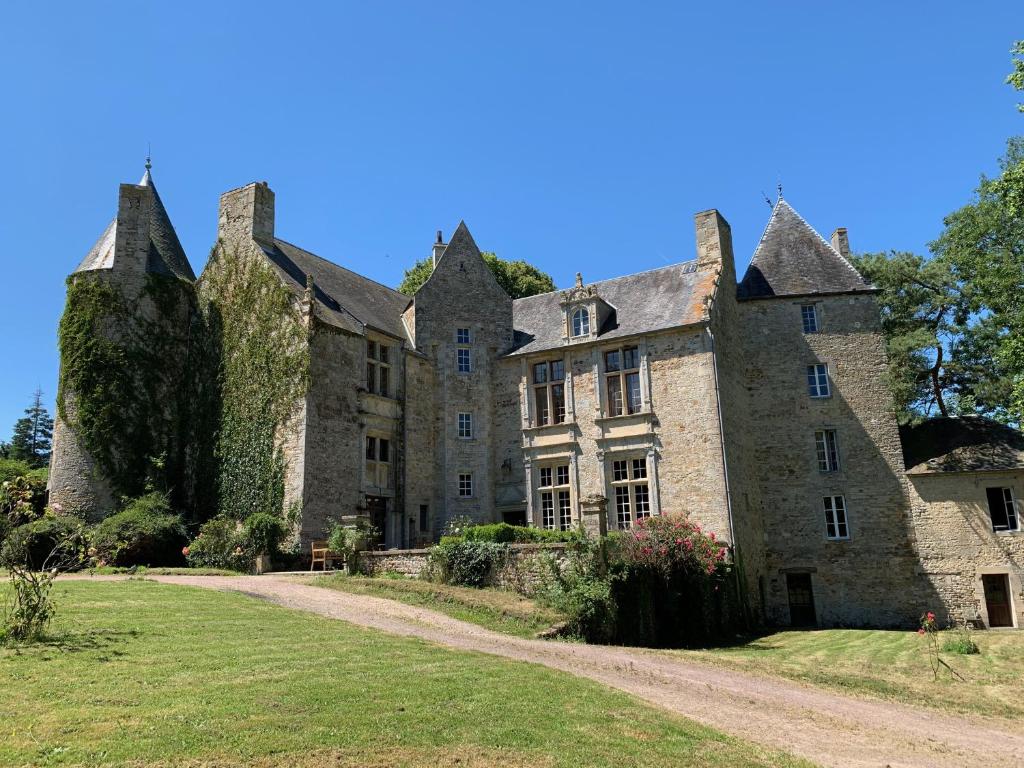 un vieux château avec une cour herbeuse devant lui dans l'établissement Château de Bernesq, à Bernesq