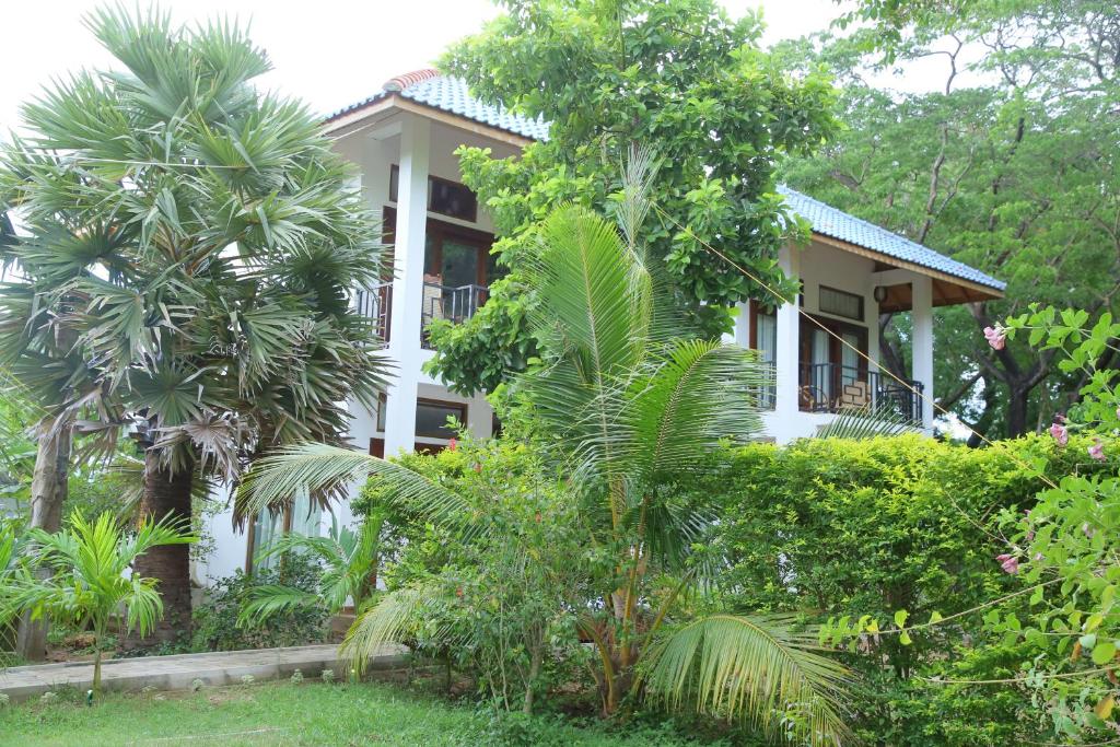 een wit huis met bomen ervoor bij Gatetrees resort in Jaffna