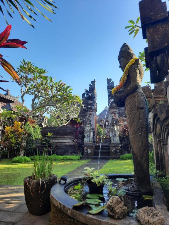 una estatua de una mujer regando un estanque en un jardín en Sahadewa House, en Ubud