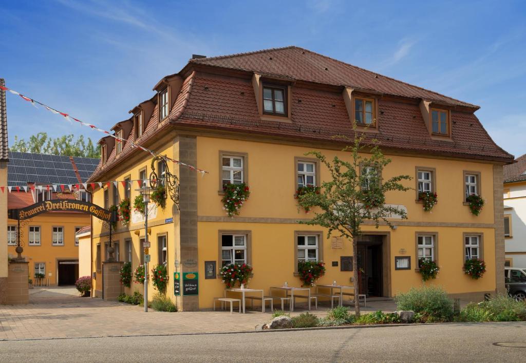 un edificio giallo con tavoli di fronte di Hotel & Brauereigasthof Drei Kronen a Memmelsdorf