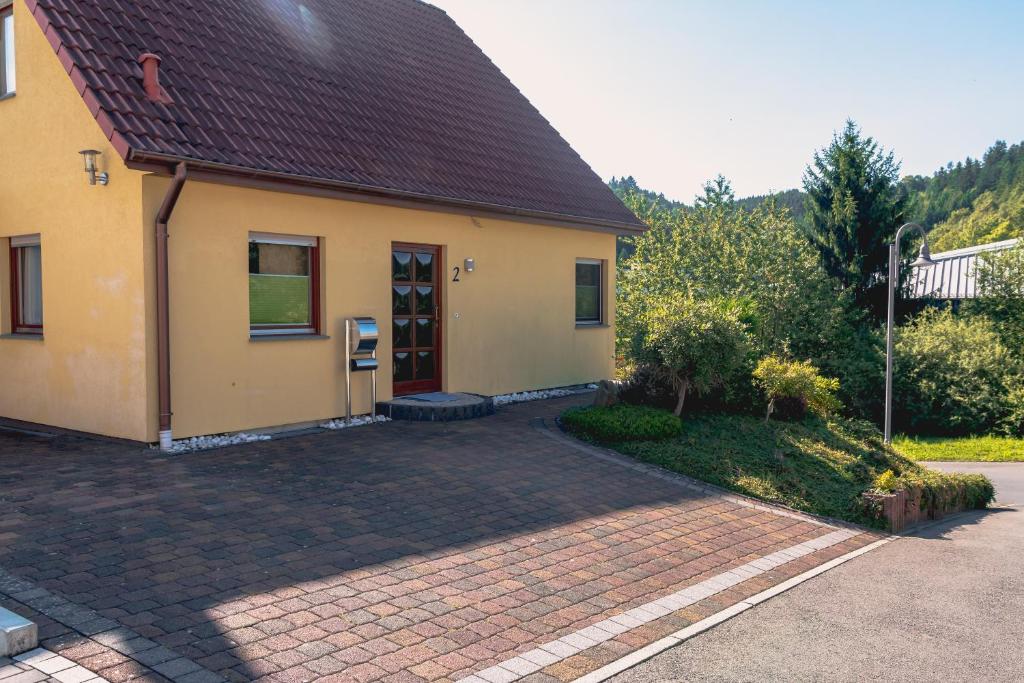 ein gelbes Haus mit einer steinernen Einfahrt davor in der Unterkunft Ferienwohnung Le in Adenau