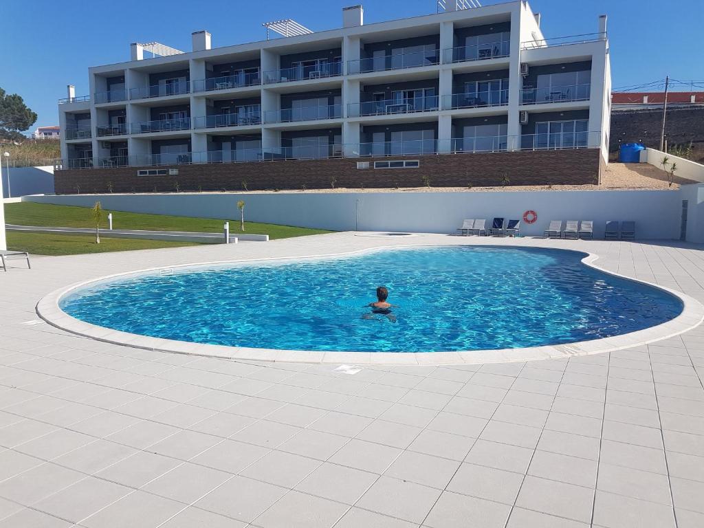 een persoon in een zwembad met een gebouw op de achtergrond bij Sonho do Mar Ap. in Nazaré