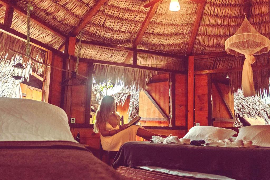 a woman sitting in a room with two beds at Raiz Kite Cabana in Jericoacoara