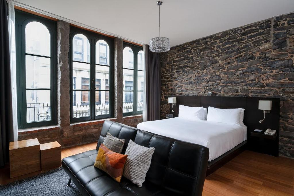 um quarto com uma cama e um sofá de couro em Le Petit Hôtel Vieux-Montréal - Saint-Paul by Gray Collection em Montréal