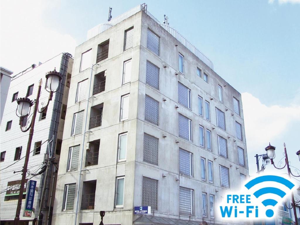 um edifício branco com um sinal de wi-fi gratuito em frente em HOTEL LiVEMAX BUDGET Yumoto em Iwaki