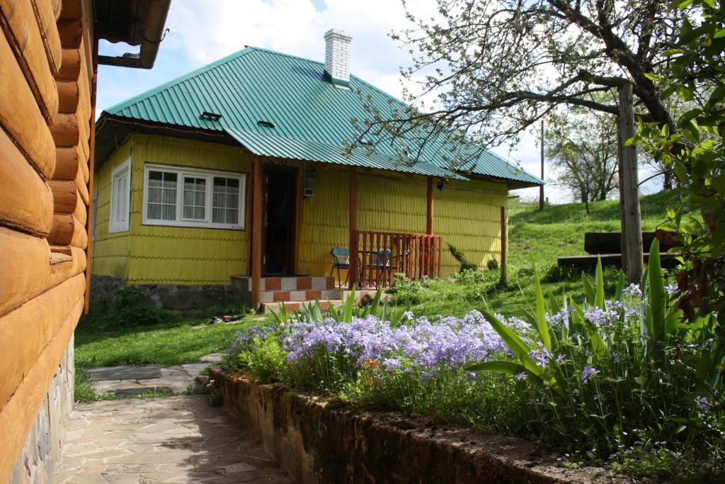 een geel huis met paarse bloemen ervoor bij Sadyba Lukacha in Zhdenievo