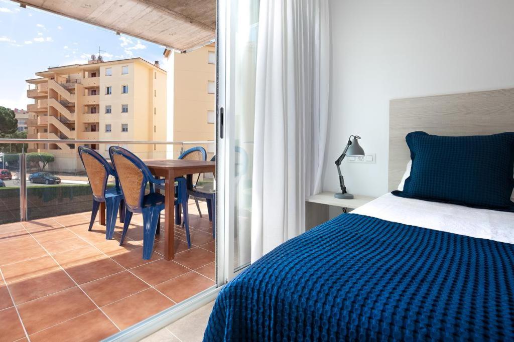 a bedroom with a bed and a balcony with a table and chairs at NIDO 150 Mestral in Roses