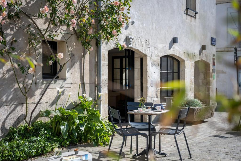 une terrasse avec une table et des chaises devant un bâtiment dans l'établissement Le Saint-Nicolas, à La Rochelle