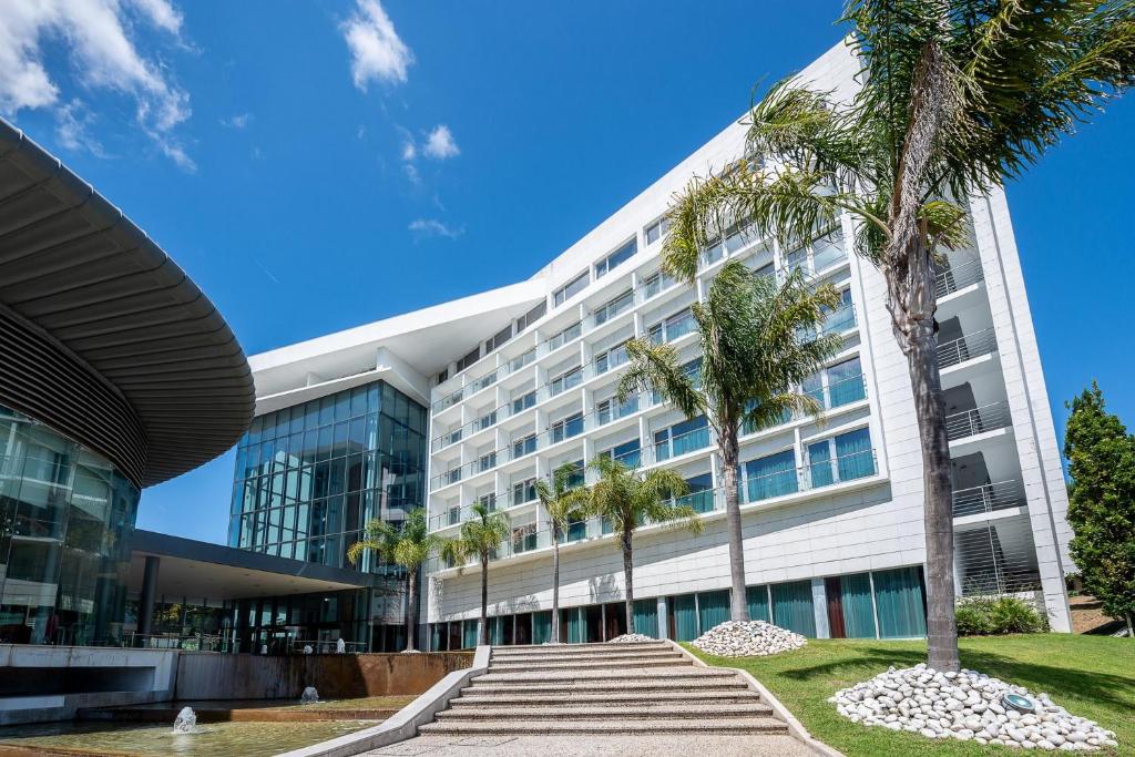 un edificio con palme di fronte ad esso di Lagoas Park Hotel a Oeiras