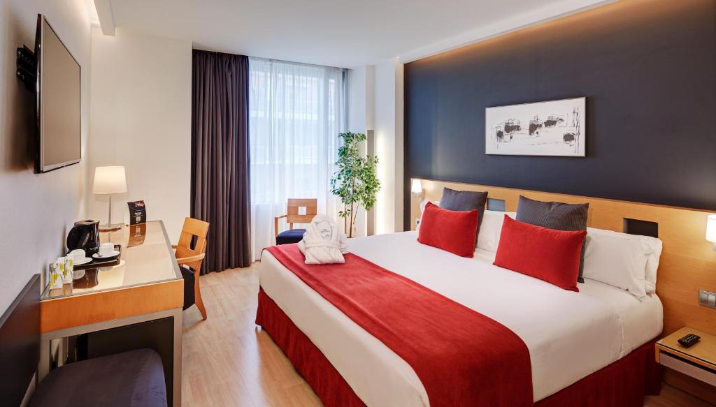 een hotelkamer met een groot bed met rode kussens bij Sercotel Caspe in Barcelona