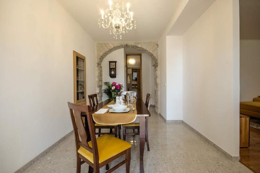 ein Esszimmer mit einem Tisch mit Stühlen und einem Kronleuchter in der Unterkunft Apartment Derossi in Umag