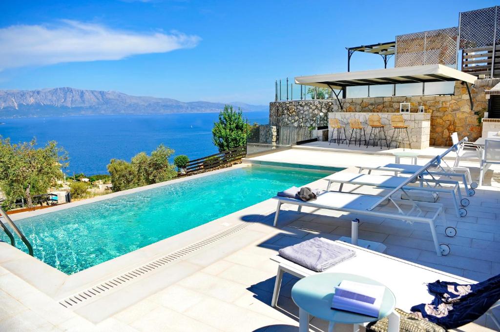 uma piscina com cadeiras e vista para o oceano em Ionian Stone Luxury Villas em Nikiana