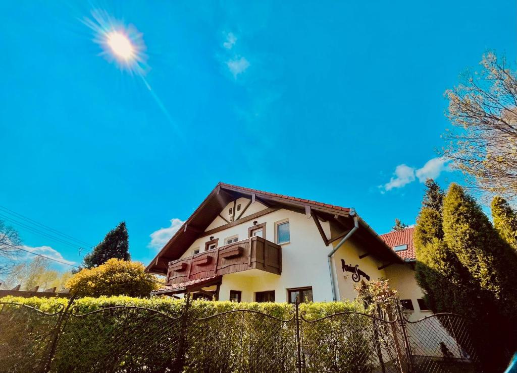 uma casa atrás de uma cerca com um céu azul em Sommer Panzió em Balatonföldvár