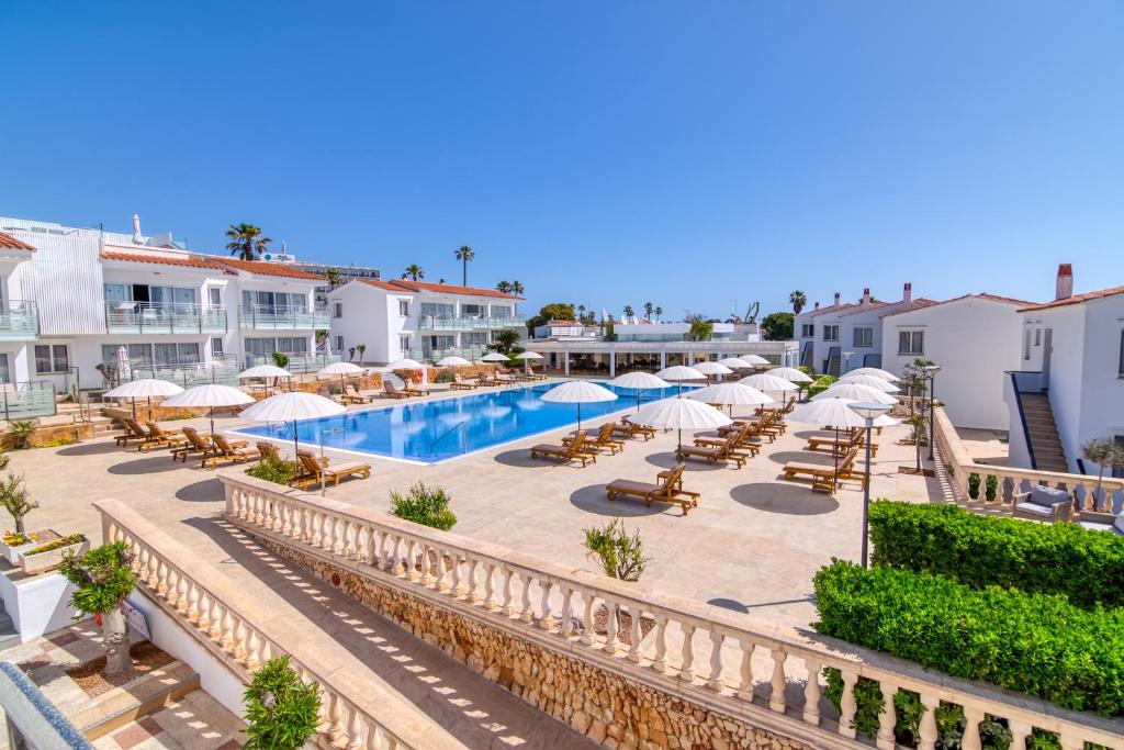 een resort met een zwembad, stoelen en parasols bij Naranjos Resort Menorca in S'Algar