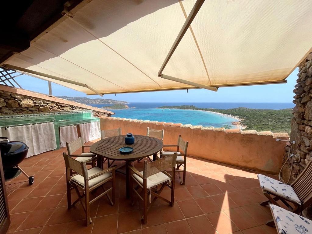 een tafel en stoelen op een patio met uitzicht op de oceaan bij SAN TEODORO PUNTA EST STUPENDO TRILOCALE VISTA MARE in Capo Coda Cavallo