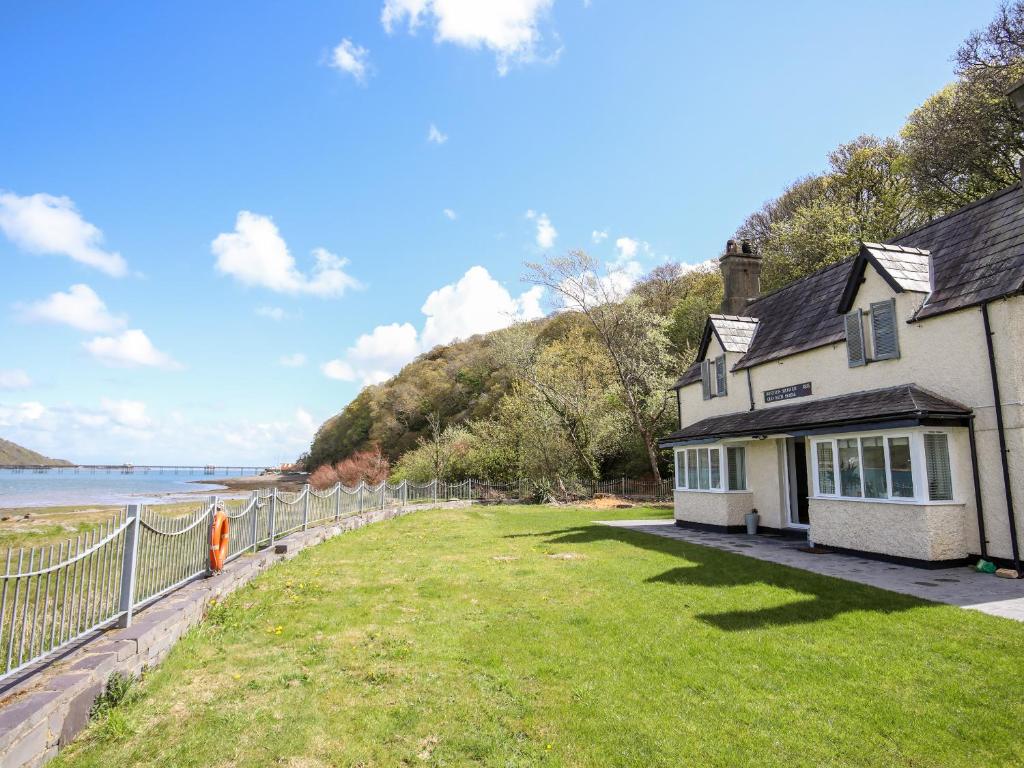 a house with a yard next to the ocean at Bwthyn Siliwen Old Bath House in Bangor