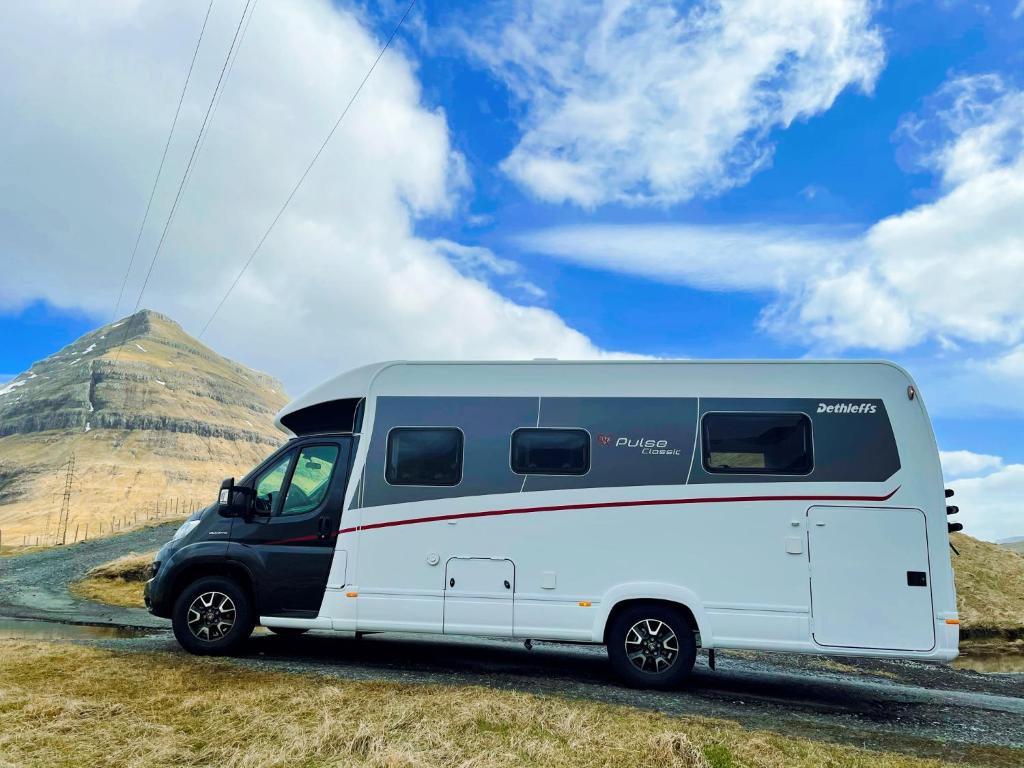 uma carrinha branca estacionada em frente a uma montanha em Autocamper Tórshavn em Tórshavn