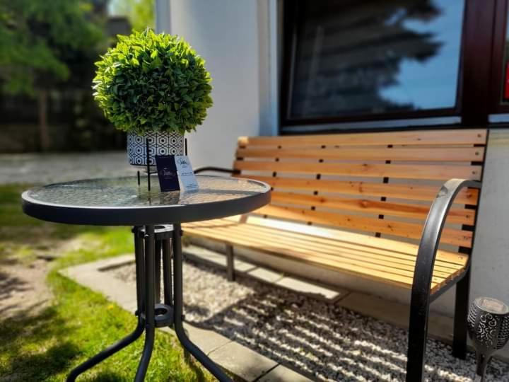 uma mesa com um vaso de plantas sentado ao lado de um banco em Villa na Dolnej em Karpacz