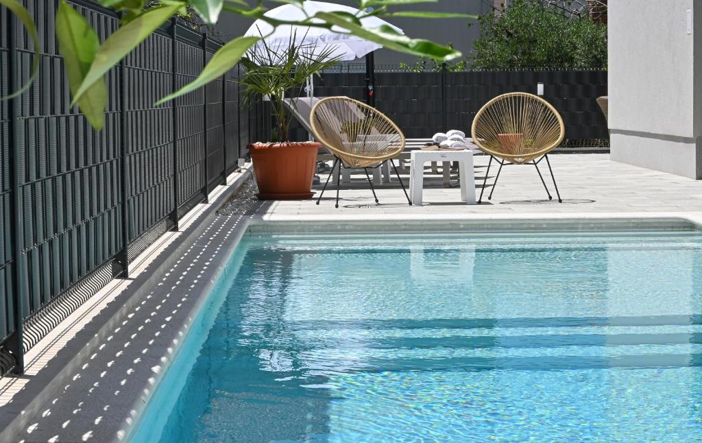 a pool with two chairs and a table next to a fence at Luxury Apartment Maravic with Private Pool in Trogir