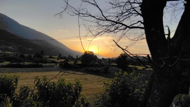 un coucher de soleil dans un champ avec le coucher de soleil derrière une montagne dans l'établissement Bujtina Polimen, à Përmet