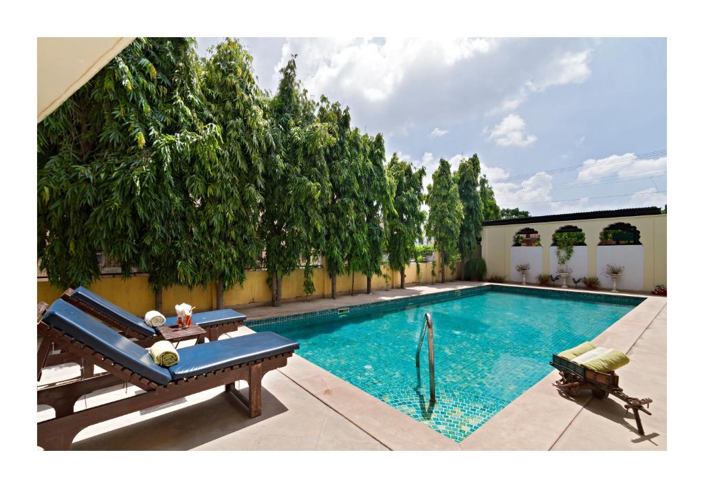 - une piscine avec deux bancs à côté d'un bâtiment dans l'établissement Dera Rawatsar - Heritage Hotel, à Jaipur