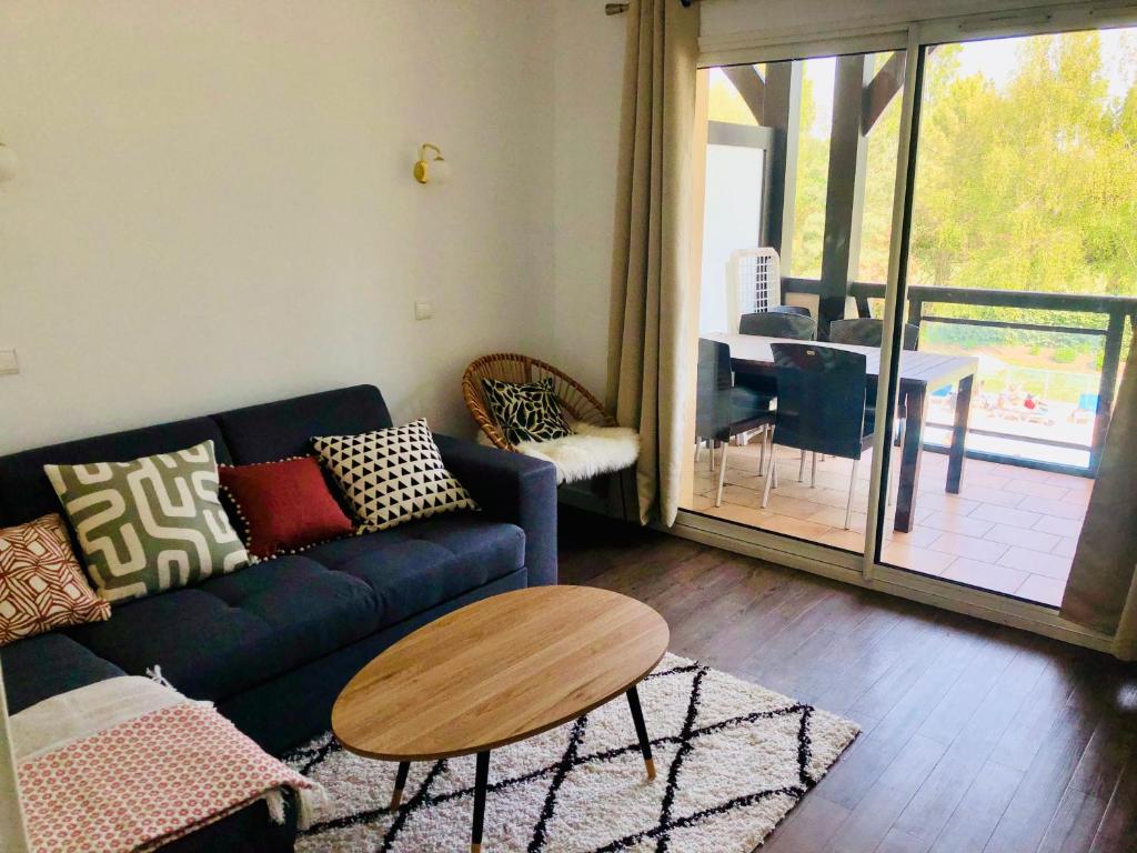 un soggiorno con divano blu e tavolo di Bel appartement cosy en résidence avec piscine a Deauville