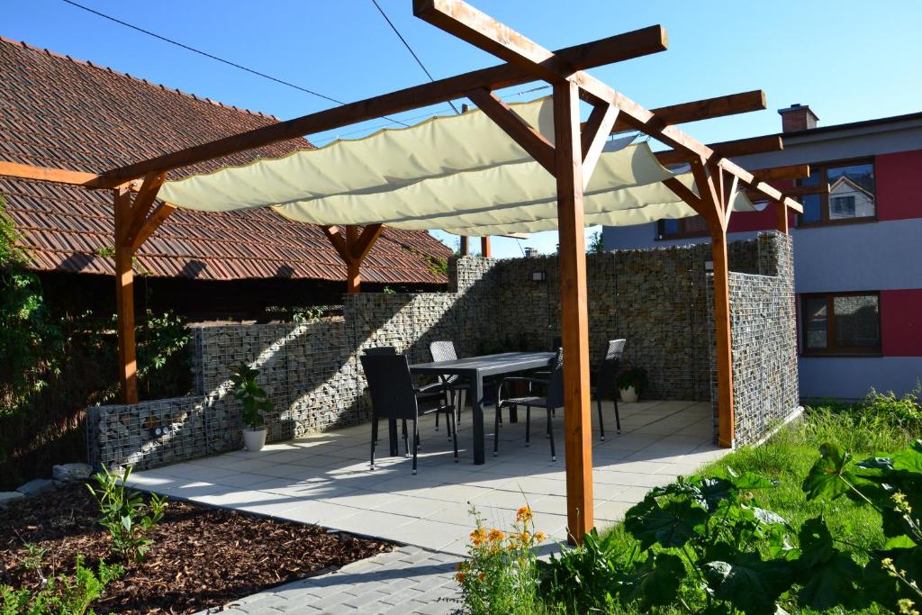 a wooden pergola with a table and chairs under it at apartmány LUHA in Luhačovice