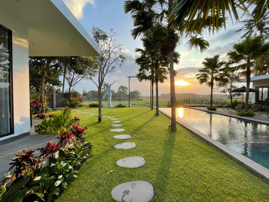 a garden with rocks in the grass next to a pool at The Valerian Villa Ubud in Ubud