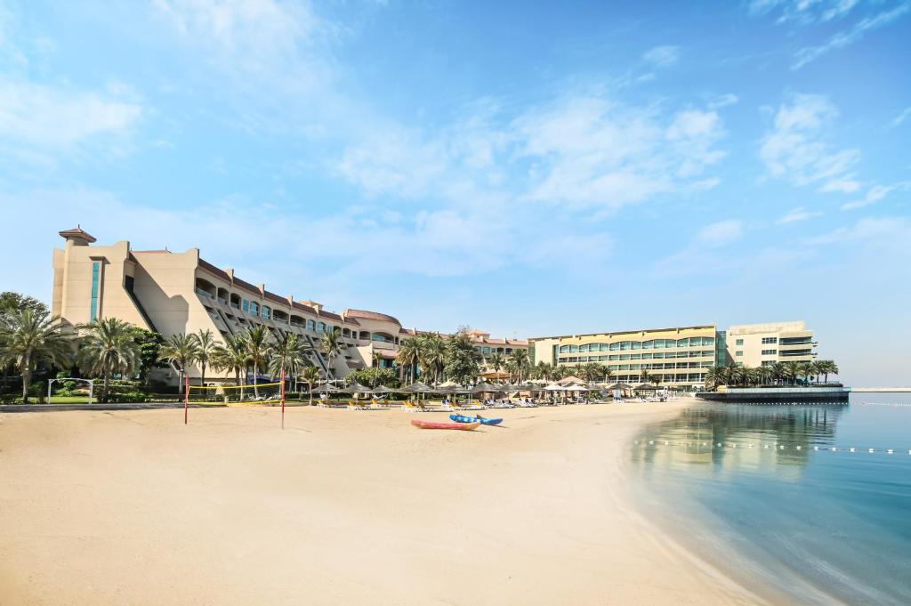 een zandstrand met gebouwen en de oceaan bij Al Raha Beach Hotel in Abu Dhabi