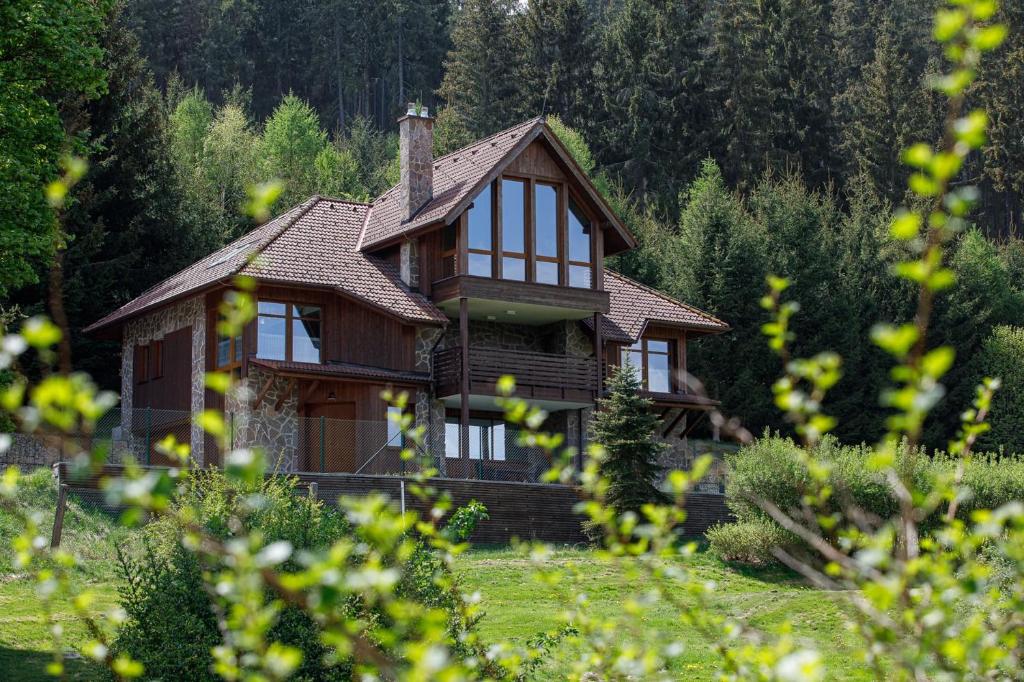 une maison en bois avec des fenêtres dans un champ dans l'établissement Hotel Villa Golf Cihelny, à Karlovy Vary