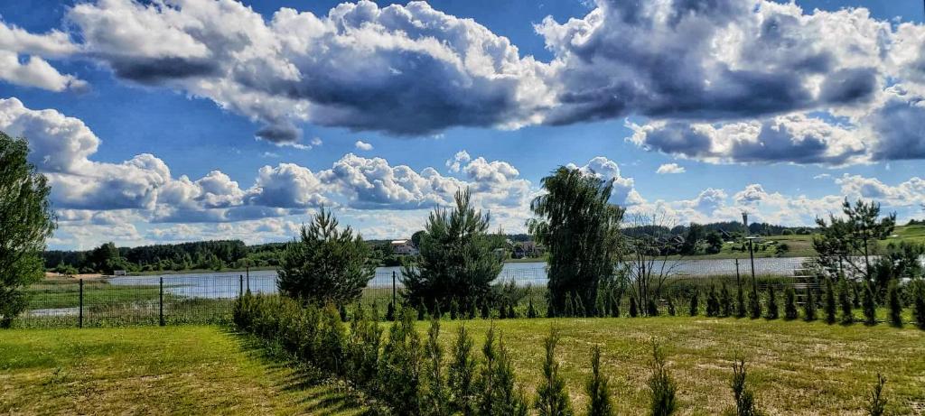 un campo con un río y nubes en el cielo en Gilužio Rivjera, en Vilna