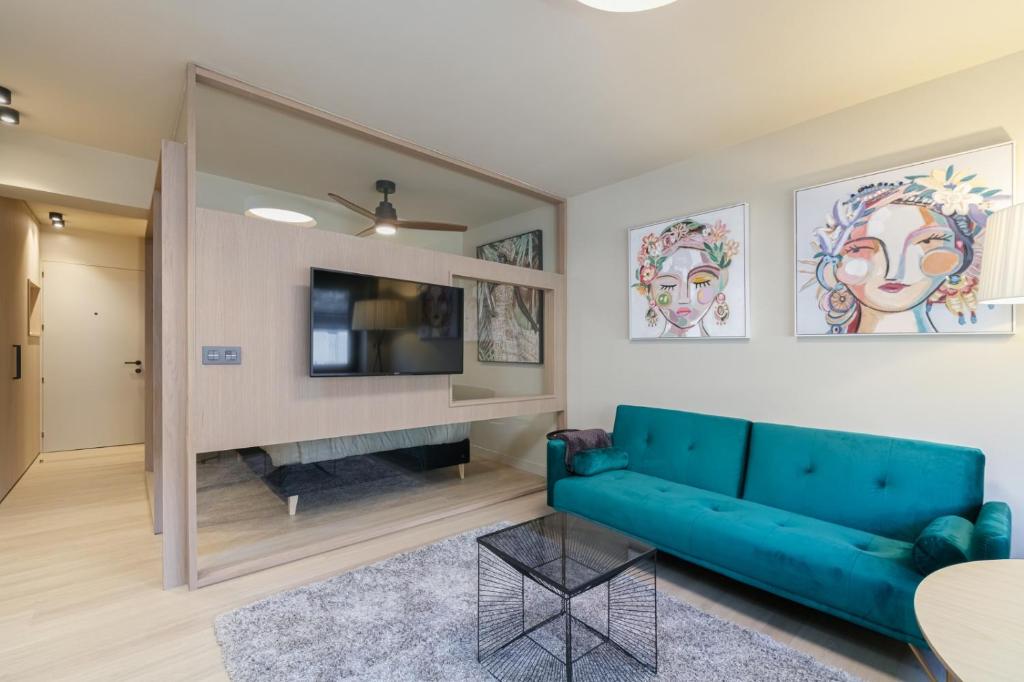 ein Wohnzimmer mit einem blauen Sofa und einem TV in der Unterkunft SUITE DE LUJO PUERTA DEL SOL+Parking in Vigo