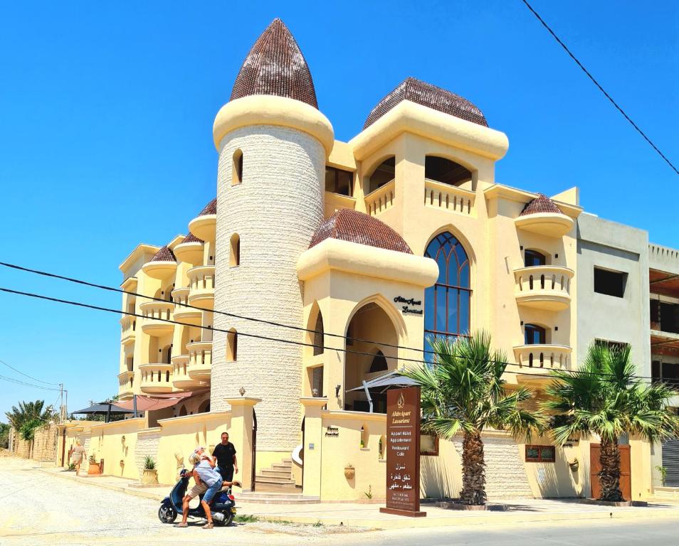 un grupo de personas montando un scooter delante de un edificio en Mahdia - Baghdadi - Laourient Apartments, restaurant, café, en Mahdia