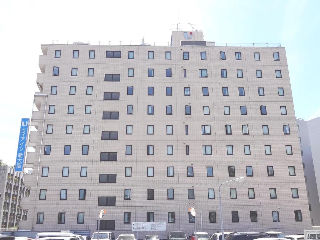 un gran edificio con coches estacionados frente a él en Via Inn Shin Osaka, en Osaka