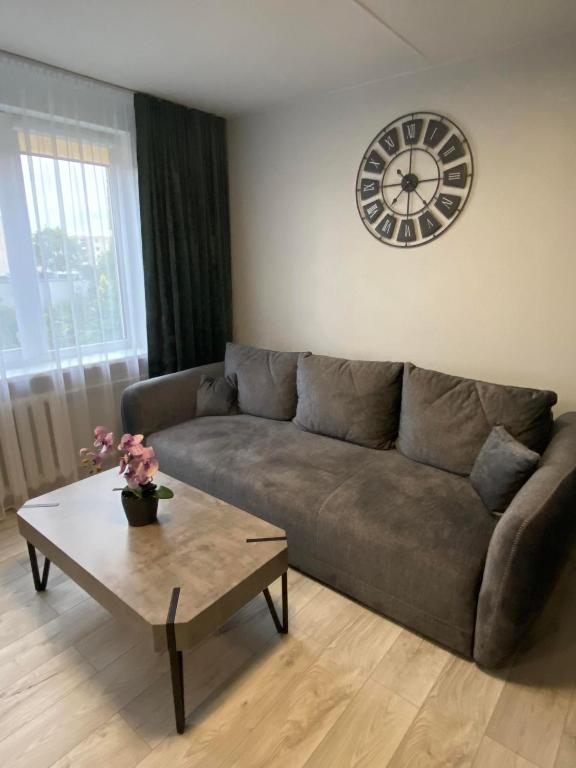 a living room with a couch and a clock on the wall at ADI Apartamentai in Panevėžys