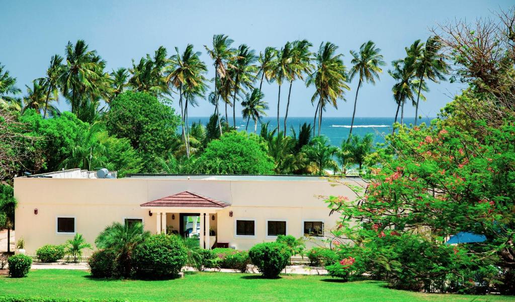 una casa con palme e l'oceano sullo sfondo di Mzima Beach Residences - Diani Beach a Diani Beach