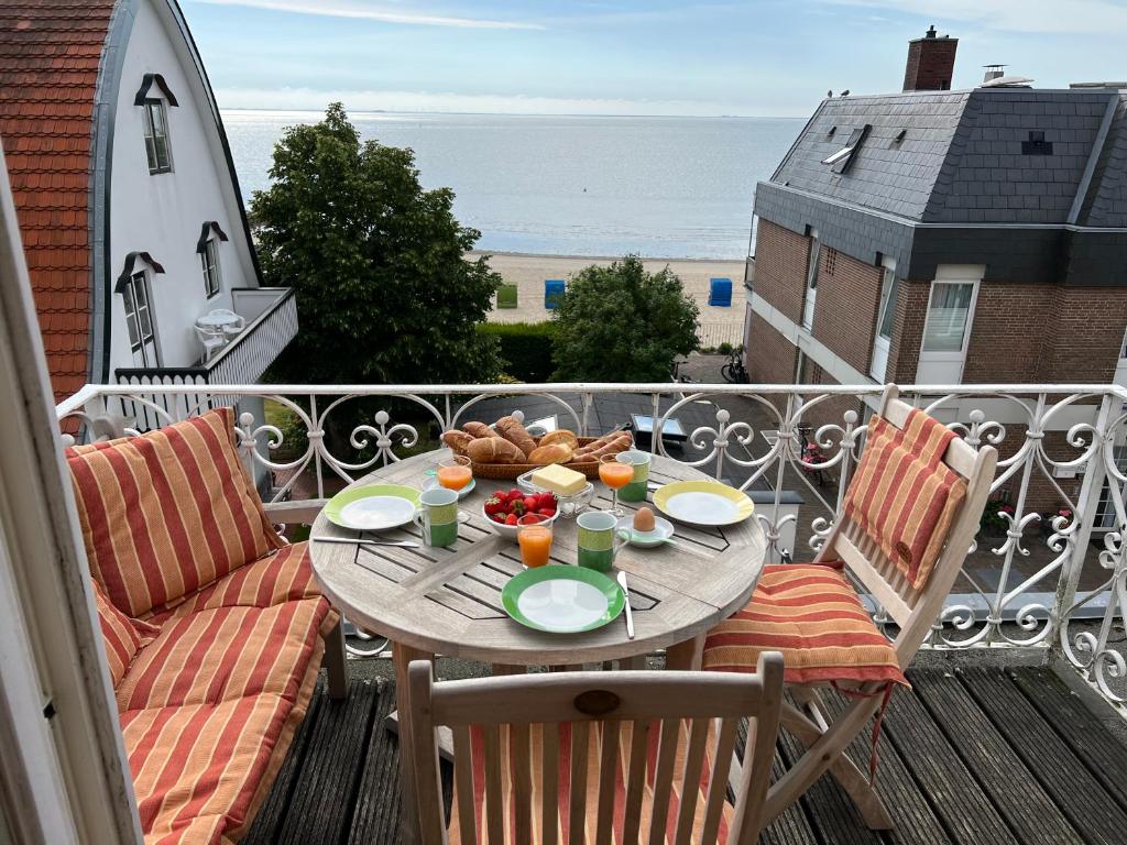 une table avec une assiette de nourriture sur un balcon dans l'établissement Sandwallkoje, à Wyk auf Föhr