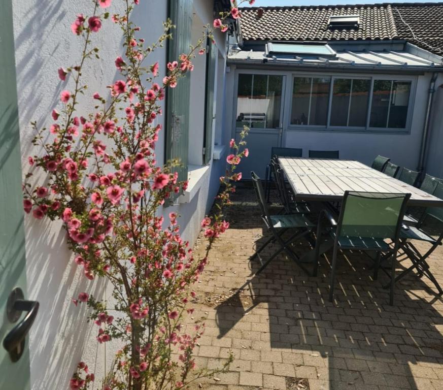 una mesa y sillas en un patio con flores rosas en Villa Babeth by Nuits au Port, en La Rochelle