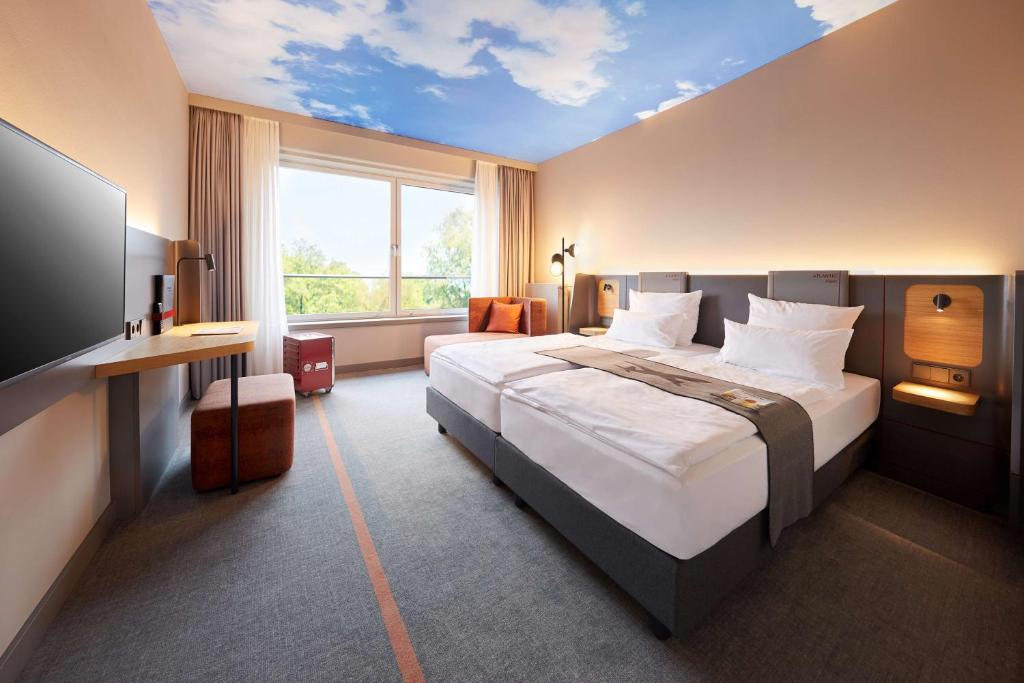 a bedroom with a large bed and a window at ATLANTIC Hotel Airport in Bremen