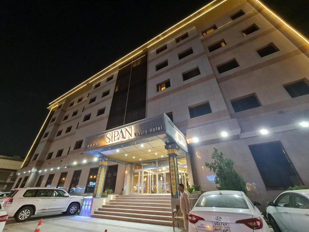 een gebouw waar auto's voor geparkeerd staan bij Sipan Hotel in Erbil