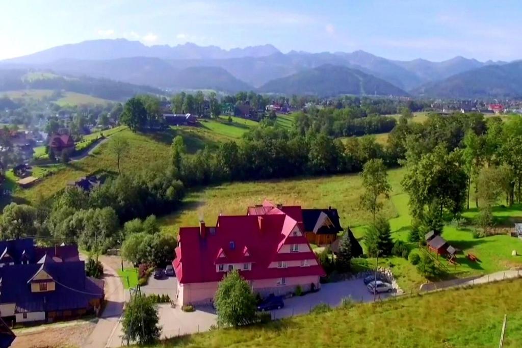 une maison dans un champ avec des montagnes en arrière-plan dans l'établissement Tatrzańska Rezydencja pod Brzyzkiem, à Zakopane