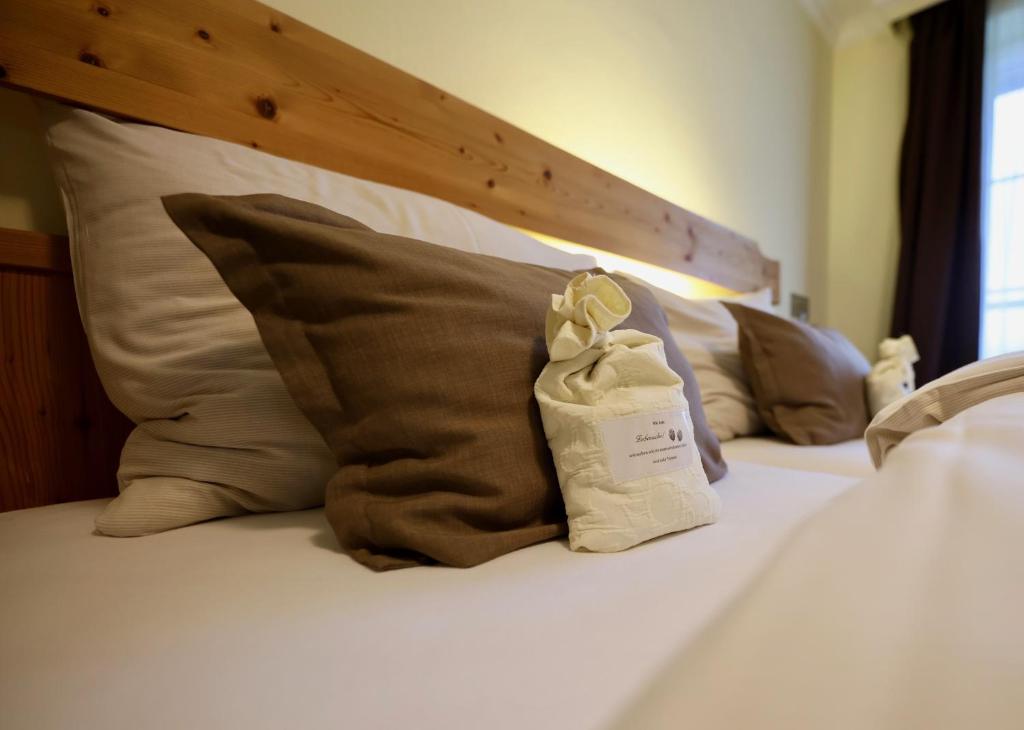 Una cama con almohadas marrones y una bolsa blanca. en Hotel Kreutzer, en Tauplitz