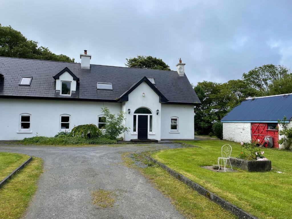 une maison blanche avec un toit noir et une allée. dans l'établissement Kerry Country House, 