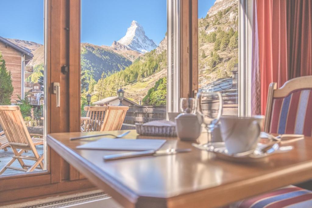 a table with a view of a mountain through a window at Antares Hotel in Zermatt