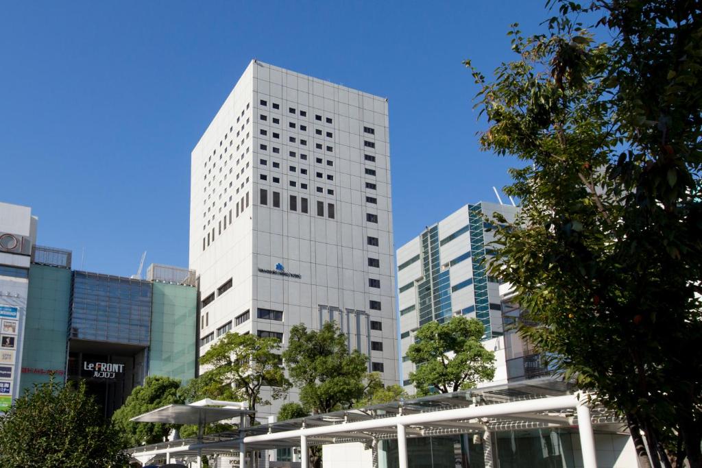 Un alto edificio bianco nel mezzo di una città di Kawasaki Nikko Hotel a Kawasaki