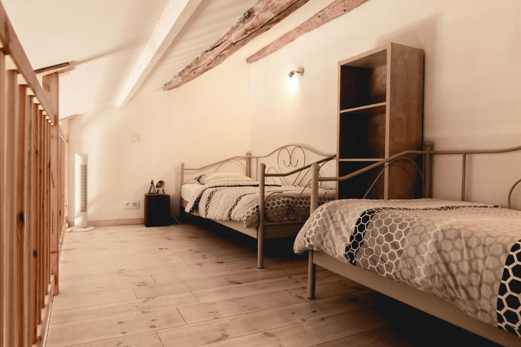 a bedroom with two beds and a wooden floor at Il était une fois in Herbeumont