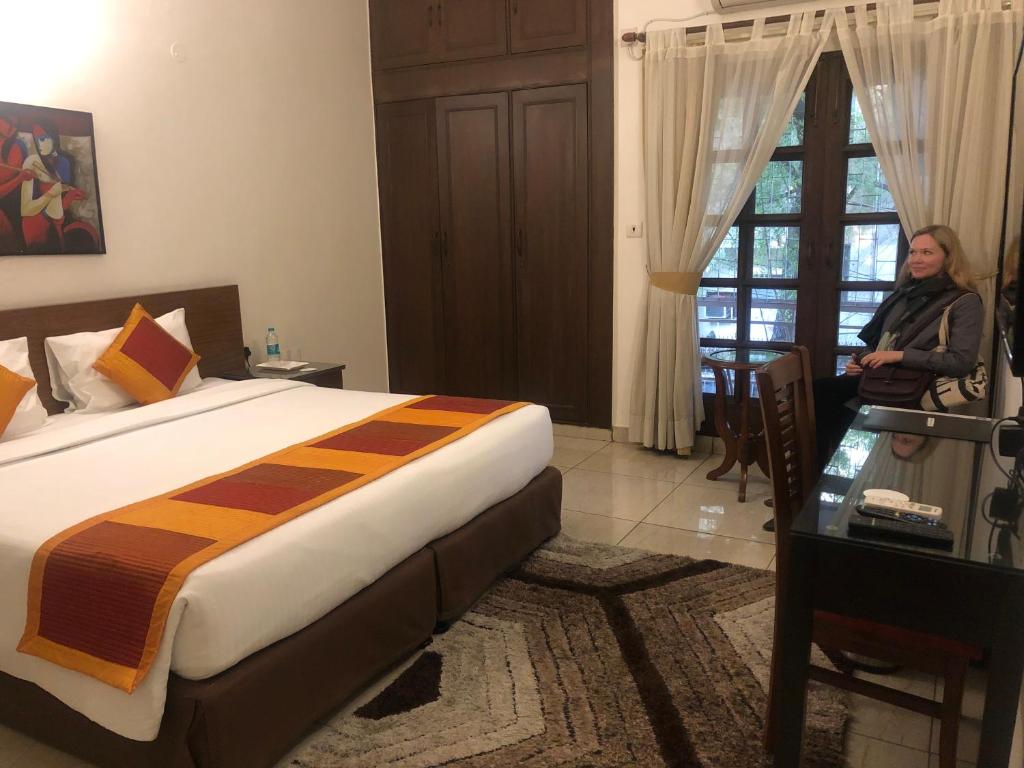 Eine Frau steht in einem Hotelzimmer mit einem Bett in der Unterkunft The Neem in Neu-Delhi