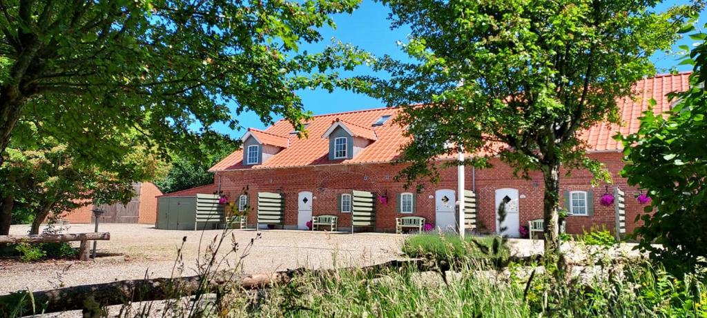 un grande edificio in mattoni rossi con alberi di fronte di Lustrup Farmhouse a Ribe